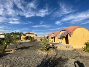 Mandīshah的住宿－Oasis inn House，沙漠中一座黄色的建筑,有红色的屋顶