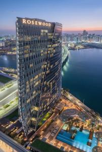 a tall building with a sign on it next to a body of water at Rosewood Abu Dhabi in Abu Dhabi