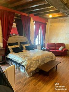 a bedroom with a large bed and a red couch at Escapade Romantique in Les Roches-lʼÉvêque