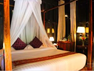 ルアンパバーンにあるNamkhan View Luangprabang Resortのベッドルーム(天蓋付きベッド、枕付)