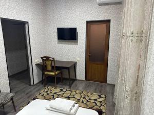 een kamer met een tafel, een stoel en een tv bij REAL TASHKENT Inn in Tasjkent
