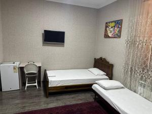 Habitación con 2 camas, escritorio y TV. en REAL TASHKENT Inn, en Tashkent