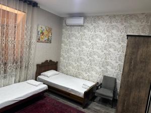een kamer met 2 bedden en een stoel. bij REAL TASHKENT Inn in Tasjkent