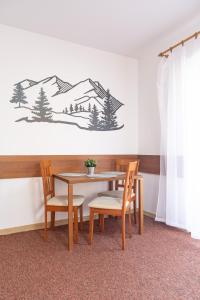 una mesa y sillas en una habitación con una foto de las montañas en Family & Friends Apartment, en Veľká Lomnica