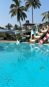 een groot zwembad met stoelen en palmbomen bij Tulsi Paradise Resort in Nirmal