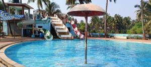 een zwembad met een glijbaan en een parasol bij Tulsi Paradise Resort in Nirmal