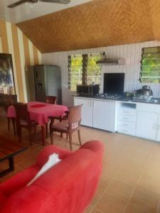 a living room with a red table and a kitchen at Orchid Island one bedroom Bure in Pacific Harbour