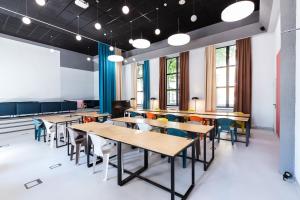 a classroom with tables and chairs and windows at Solo Society Kaunas Apartments in Kaunas