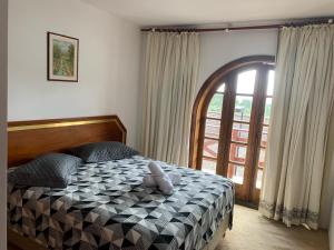 1 dormitorio con cama y ventana grande en QUATRE SAISONS RESIDENCE em Campos do Jordão Completo até 6 Hóspedes en Campos do Jordão