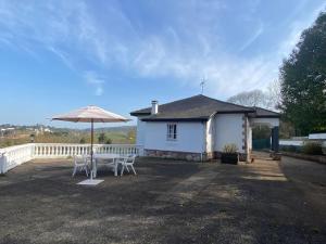 a white house with a table and an umbrella at La Costana - San Cucao de Llanera in Agüera