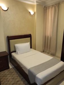 Liberty Avenue Hotel في الدوحة: غرفة نوم بسرير وملاءات بيضاء ونافذة