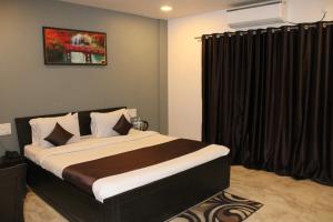 Schlafzimmer mit einem großen Bett und schwarzen Vorhängen in der Unterkunft Harmony Palace in Mahabaleshwar