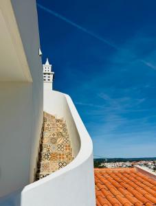 a white building with a clock tower on top of a roof at Palm View Guesthouse, adults only in Luz