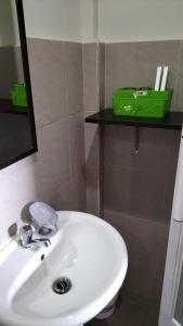 a white sink in a bathroom with a green box on a shelf at G Hotel in Dauis