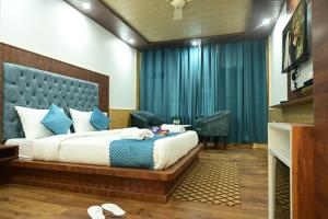 a bedroom with a large bed with blue curtains at Hotel Nirvana Hills With Balcony Rooms And Open Terrace in Manāli