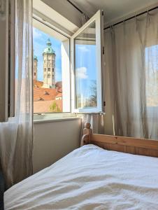 ein Schlafzimmer mit einem Fenster mit Blick auf einen Turm in der Unterkunft Spechtnest in Naumburg