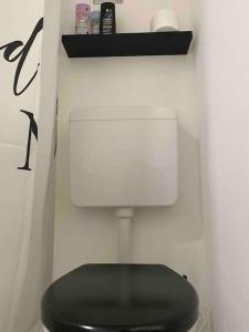 La salle de bains est pourvue de toilettes noires dans un mur blanc. dans l'établissement Modernes City Apartment Bayreuth, à Bayreuth
