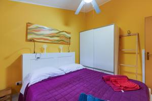 um quarto com uma cama roxa e uma ventoinha de tecto em Home Holidays Pintadera 1 em Bosa
