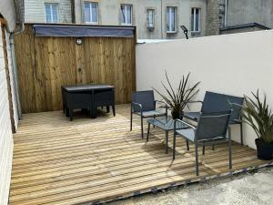 een patio met stoelen en een tafel op een houten terras bij Chez FanF & Nanie in Isigny-sur-Mer