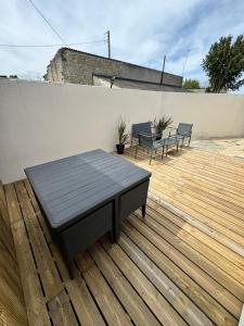 een patio met 2 stoelen en een tafel op een houten terras bij Chez FanF & Nanie in Isigny-sur-Mer