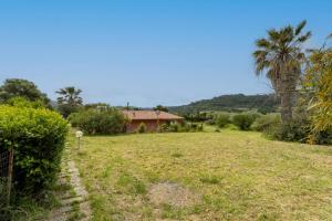a field with a house in the background at Home Holidays Pintadera 1 in Bosa