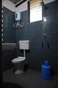 baño con aseo y lavabo y ventana en Arpita FarmStay, en Malvan