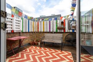 a balcony with a bench and a fence with flags at GuestReady - Artsy Penthouse in Heart of the City in London