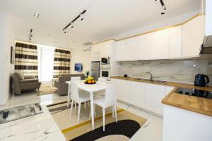 uma cozinha com armários brancos e uma mesa e cadeiras brancas em Tesi Apartment em Vlorë