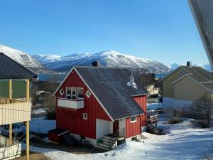 a red house in the snow with mountains in the background at Polar Arctic Luxury House - Free parking in Tromsø