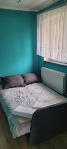 łóżko w sypialni z niebieską ścianą w obiekcie Spokojne i miłe miejsce na Mazurach w mieście Kętrzyn