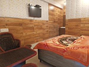 - une chambre avec un lit et une télévision murale dans l'établissement Rising Spring, à Dharamshala