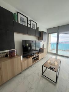 a living room with a large television and a table at Renthas Torre Lugano in Benidorm