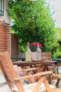 - une table en bois avec des fleurs, des bouteilles et des chaises dans l'établissement Lemon Tree House, à Vrahati