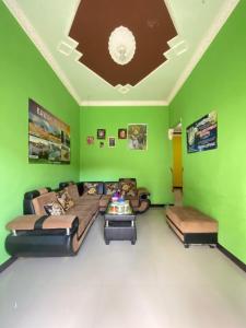 een woonkamer met een bank en een groene muur bij Ijen kingdom guest house in Tamansuruh