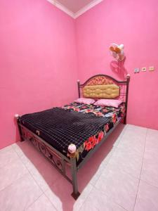 ein Schlafzimmer mit einem Bett in einer rosa Wand in der Unterkunft Ijen kingdom guest house in Tamansuruh
