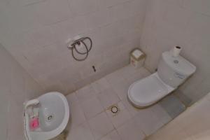 a white bathroom with a toilet and a sink at Kiriboungni chez sylfatou in Tahire