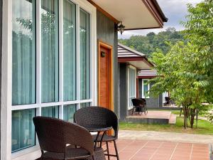 d'une terrasse avec 2 chaises et une table à côté d'une fenêtre. dans l'établissement ช่องแคบ เดอ เมาท์เท่น รีสอร์ท, à Ban Huai Nam Nak