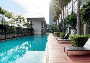a large swimming pool with benches and a building at Thapra residence,next to bts,The mall,Icon Siam,Siam Paragon,Central World in Thonhuri