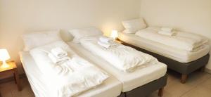 three beds in a room with white sheets and towels at Eleonoras Ferienwohnung in Würzburg Stadt am Park mit Balkon inklusive eigenen Parkplätzen vor der Tür in Würzburg