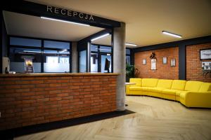 a lobby with yellow couches in a brick wall at Hotel Bastion in Malbork