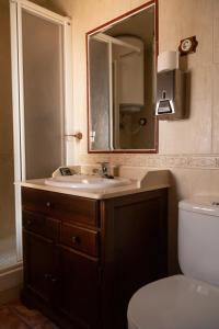 a bathroom with a sink and a mirror and a toilet at Hostal Corper Navalcarnero in Navalcarnero
