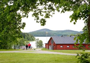 duas pessoas a passar por um celeiro vermelho com um lago em Nordvik Bed & Breakfast em Nordvik