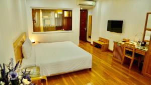 um quarto com uma cama, uma secretária e uma televisão em Blue Hanoi Hotel em Hanói