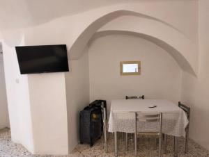 um quarto com uma mesa e uma televisão de ecrã plano em Stone Rooms em Matera