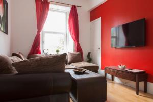 a living room with a couch and a red wall at My Meadows, City Centre Apartment, Sunny&Spacious in Edinburgh