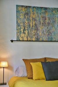 um quadro pendurado por cima de uma cama com almofadas amarelas em "La Suite" 3 Etoiles em Uzès