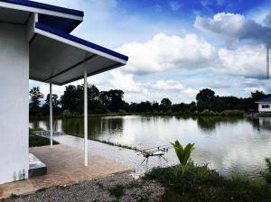 a building with a picnic table next to a lake at Chaiyaphum Monster Fishing Resort in Ban Huai Kum