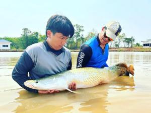 two men holding a large fish in the water at Chaiyaphum Monster Fishing Resort in Ban Huai Kum