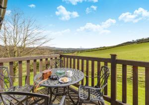 a table and chairs on a balcony with a view of a field at 2 Derw Cottages in Trefeglwys