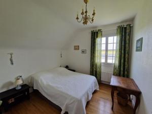 1 dormitorio con cama, ventana y lámpara de araña en Family-friendly holiday home near the coast, en Plougasnou